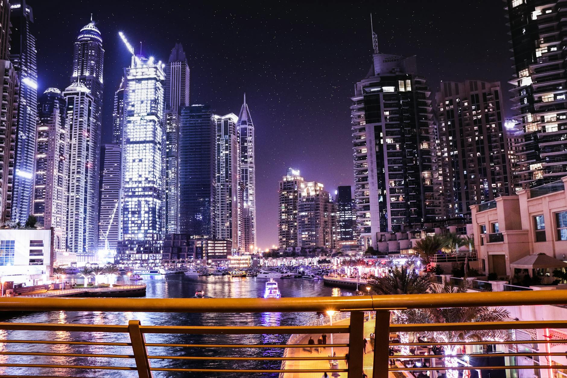 Nocna panorama Dubai Marina z oświetlonymi wieżowcami odbijającymi się w wodzie