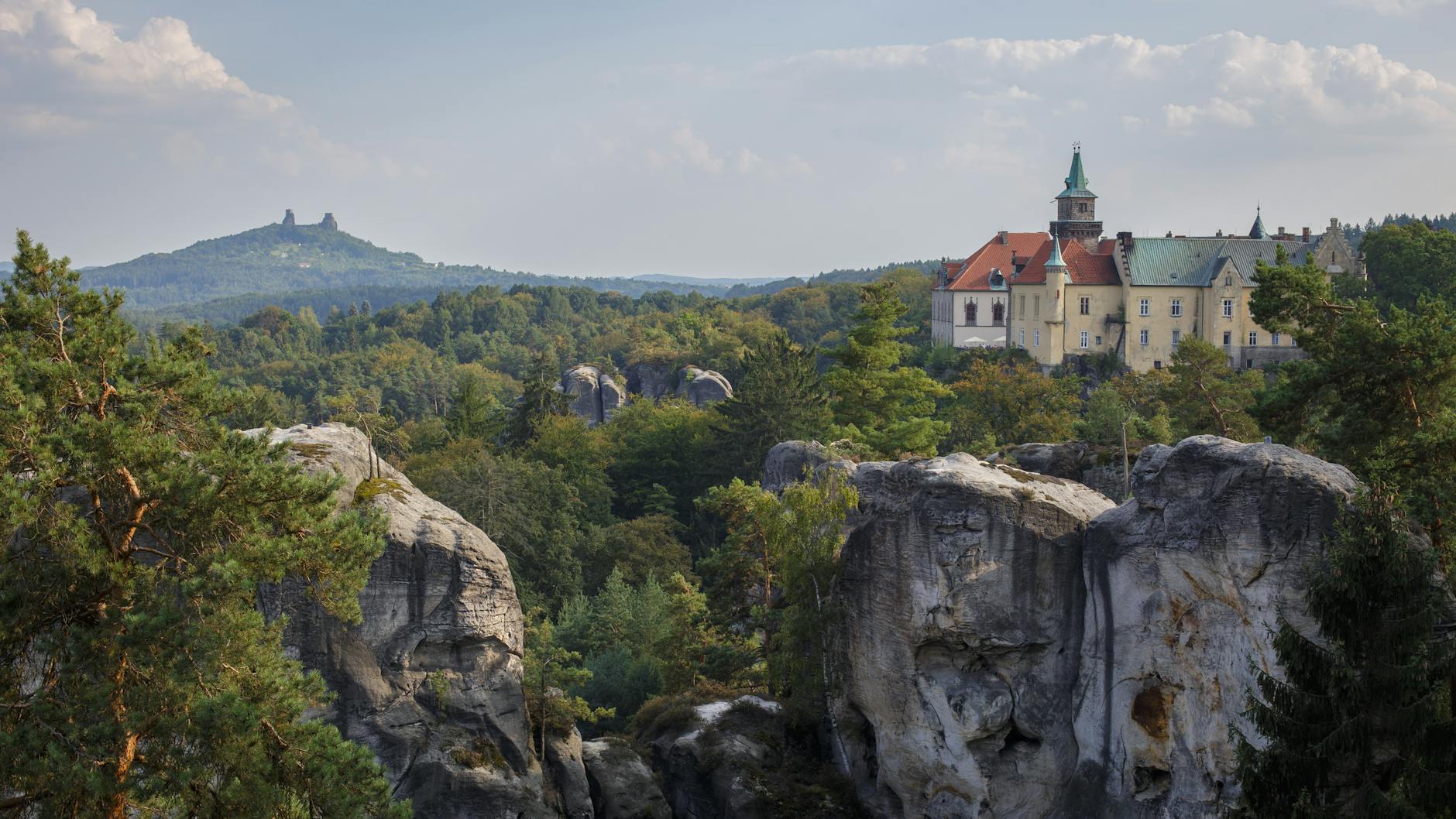 Zamek Hrubá Skála wśród skalnych formacji i zieleni w Czechach