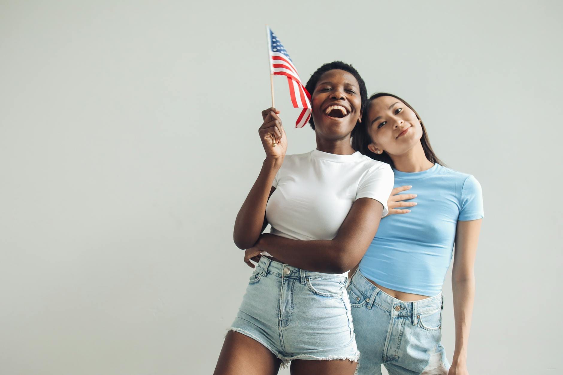 Dwie kobiety w domu radośnie unoszą dużą amerykańską flagę