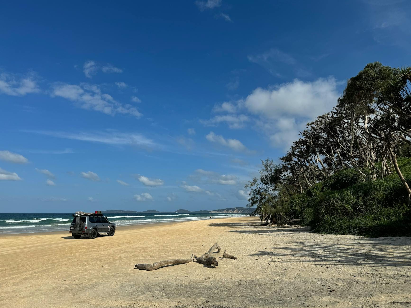 Samochód 4x4 jedzie po pustej piaszczystej plaży na australijskiej wyspie