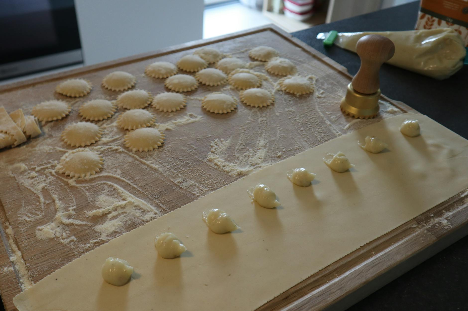 Świeże ravioli na oprószonej mąką desce z wykrawaczem do makaronu