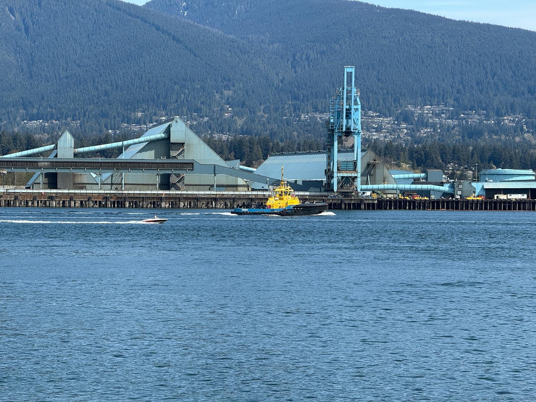 Holownik w porcie Vancouver na tle gór i przemysłowych nabrzeży