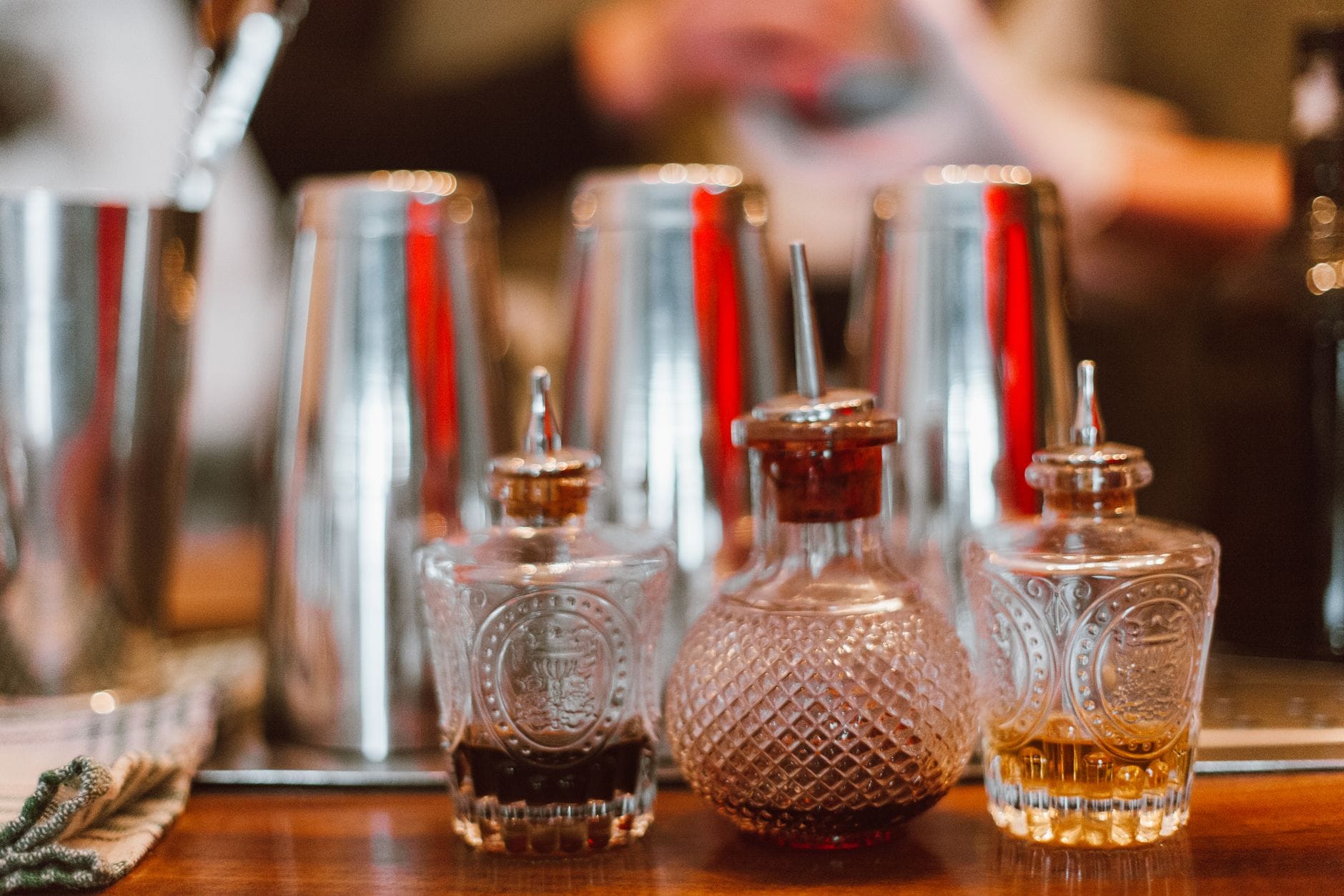 Jak zrobić domowy bitter do drinków – prosty przepis i praktyczne zastosowania Butelki z bitterem na barze obok shakerów do koktajli