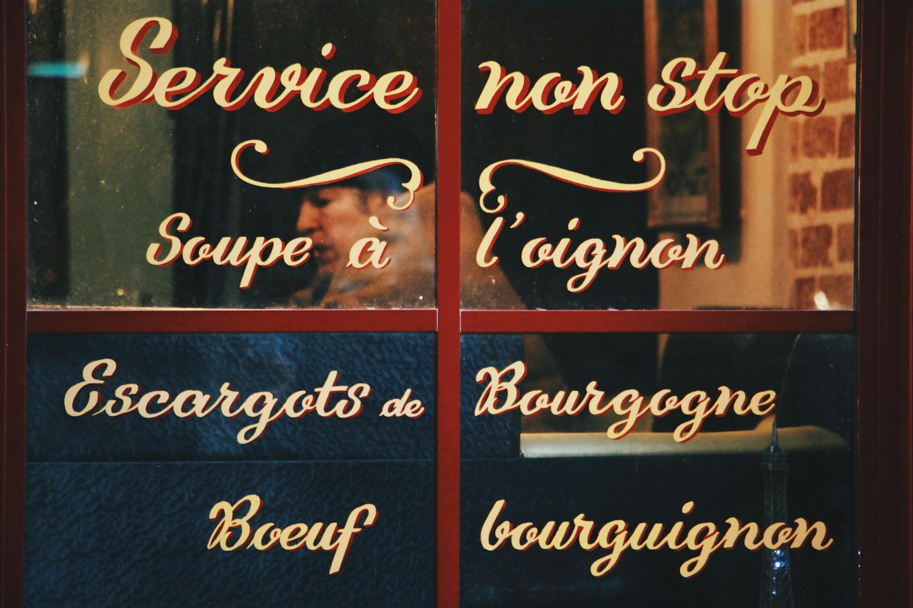 Okno francuskiego bistro z tradycyjnym menu odbijającym ulicę