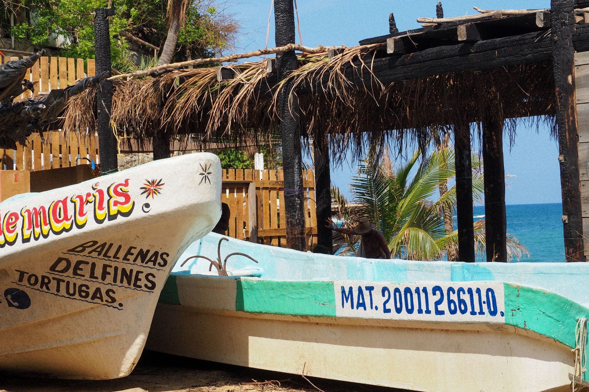 Tradycyjne łodzie rybackie i palmaowa chata na plaży w Oaxaca